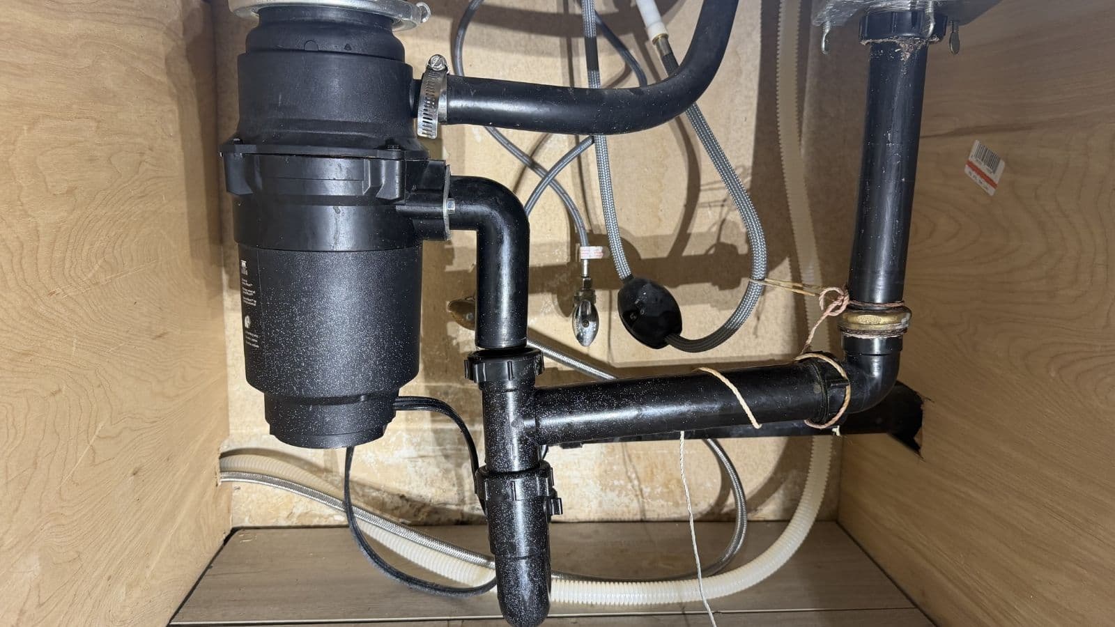 Damaged garbage disposal and improperly configured drain piping under kitchen sink in Glendale apartment near Glenoaks